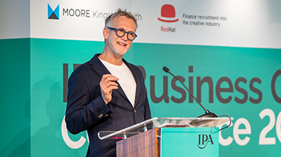 Jason Cobbold stands at a clear podium speaking into a microphone during the IPA Business Growth Conference
